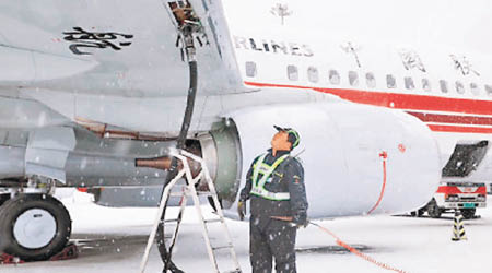 北京機場工作人員，冒風雪檢查飛機。