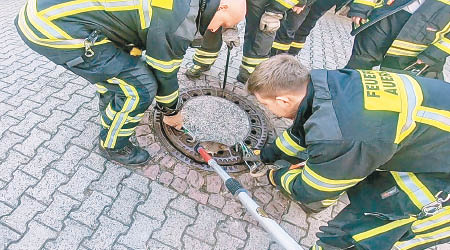 消防員合力抽起坑渠蓋。