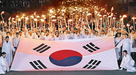 南韓民眾點起燭光，拉起國旗遊行。（美聯社圖片）