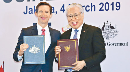 澳洲貿易部長伯明翰（左）和印尼貿易部長呂有恩（右）簽署協定。（美聯社圖片）