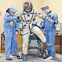 工作人員為奧夫奇尼（中）檢查太空衣。