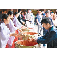 明治神宮派酒<br>東京明治神宮參拜善信人山人海，三十名穿上傳統服飾的巫女，向善信舀上一杯用傳統木角杯盛載的清酒，一千杯在半小時內派光。