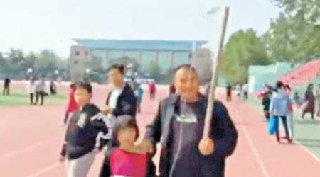 該名虎爸替女兒拿着鹽水袋參觀中學。（互聯網圖片）