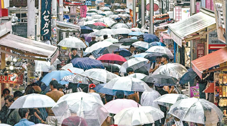 人們持傘步過市區。（美聯社圖片）