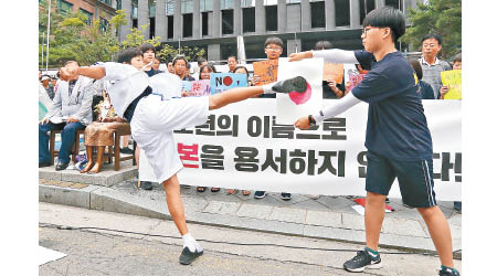 南韓小學生在日本大使館外示威，有人腳踢印有日本國旗的膠板。