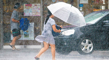 颱風襲台灣，一名持傘女子頂強風而行。（美聯社圖片）