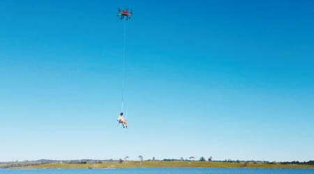 無人機吊起男子在湖泊上垂釣。