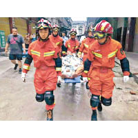 救援人員協助一名患病的長者疏散。（中新社圖片）