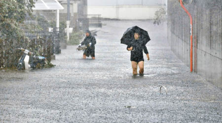 市民狼狽撐傘在路上涉水而行。（美聯社圖片）