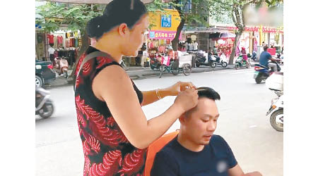 婦人在街頭擺攤，專幫顧客拔白頭髮。