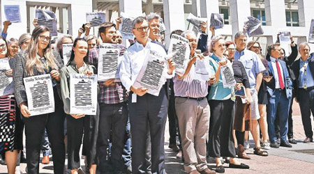 多名新聞工作者手持報章抗議。（美聯社圖片）