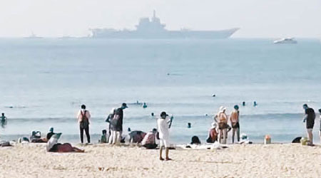 民眾在沙灘上觀看002航母進駐基地。（互聯網圖片）