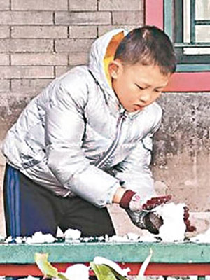 北京降下初雪，有小孩在堆雪人。
