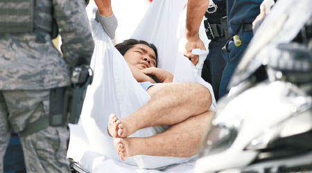 救援人員用擔架床抬走一名男子。（美聯社圖片）