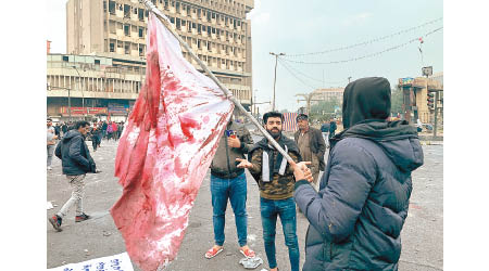 示威者手持染血的伊拉克國旗。（美聯社圖片）