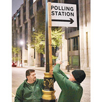 工人在街道掛起投票的指示牌。