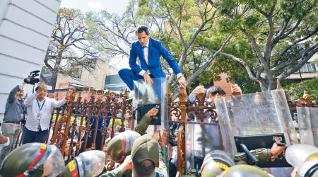 瓜伊多試圖爬過鐵閘入內。（美聯社圖片）