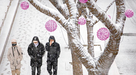 北京下雪，街上的民眾都穿上厚厚的冬衣。