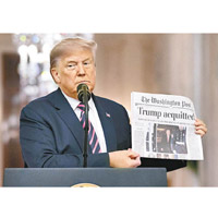 特朗普展示在頭版大字標題「無罪」的報章。