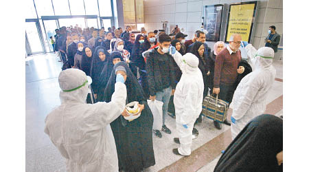 伊拉克納杰夫機場人員檢查來自伊朗的乘客體溫。（美聯社圖片）