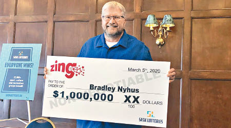 尼許斯拿着大大的獎金支票留影。