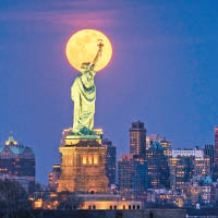 自由女神像向月高舉火炬。（美聯社圖片）