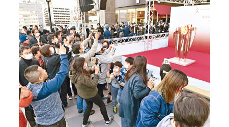 東京奧組委已着手制訂延期方案，仙台市民拍攝奧運聖火。（美聯社圖片）