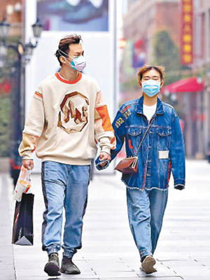 戴口罩的男女在重開的武漢商業區散步。（美聯社圖片）