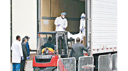 醫院人員操作剷車，把死者遺體搬到冷凍貨櫃車。