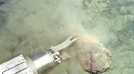 鑽探機在海底夾取岩石塊。