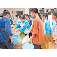 學生用水盆和水桶裝水。