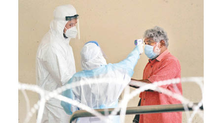 馬來西亞醫療人員為民眾探熱，防止疫情蔓延。（美聯社圖片）