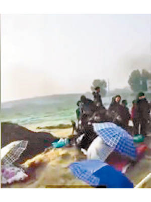 小童的遺體被布包裹放在傘下。