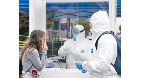 洛杉磯消防部門人員身穿保護衣，為民眾檢測病毒。（美聯社圖片）