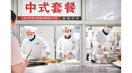 在北京市一間工廠的飯堂內，職員處理食物時戴口罩及手套。
