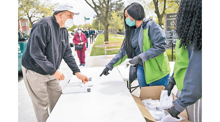 美國疫情持續，紐約市公園管理人員向民眾派口罩。