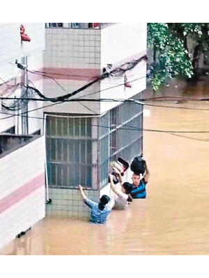 民眾抓着窗框艱難前行，以防被洪水沖走。