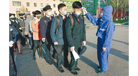 在北韓平壤，學生回校時量度體溫。（美聯社圖片）