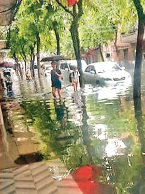 大雨導致街道水浸，民眾涉水而行。