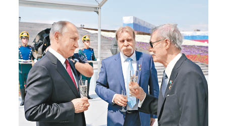 普京（左）公開露面，在國慶日升旗禮與來賓交談。（美聯社圖片）