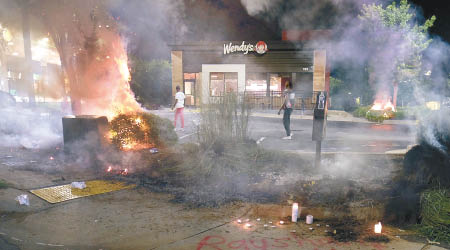 示威者縱火燒毀快餐店。（美聯社圖片）