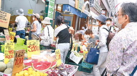 日本防疫措施放寬，民眾未敢鬆懈，戴口罩購物。（美聯社圖片）