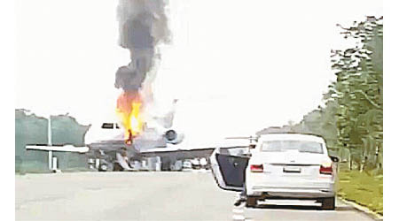 小型機降落在路面上，機身起火烈燄沖天。