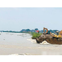 救援人員出動挖泥機修補河堤決口。