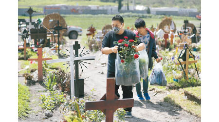 墨西哥的新冠肺炎死亡率高企，家屬到墓地拜祭死者。（美聯社圖片）