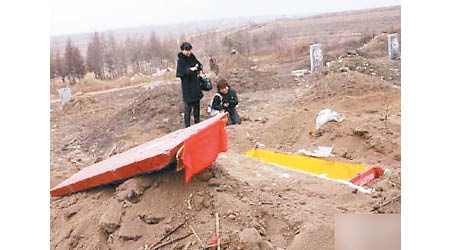 有死者家屬在被挖走遺體的墓前痛哭。