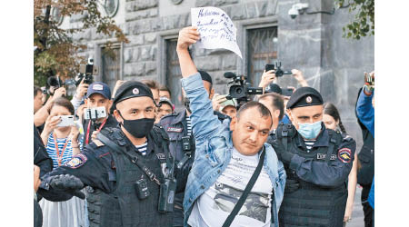 納瓦尼一名支持者（中）在聯邦安全局大樓外示威被捕。（美聯社圖片）
