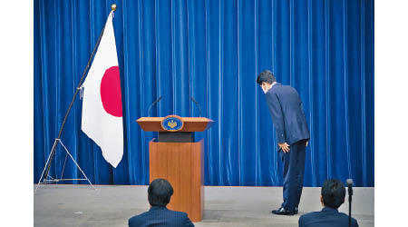 安倍晉三向日本國旗鞠躬。（美聯社圖片）
