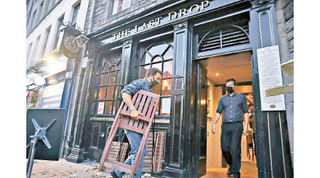蘇格蘭愛丁堡的酒吧員工收拾店外的椅子。（美聯社圖片）
