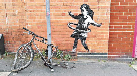畫中女童在一輛沒有後轆的真單車旁玩呼啦圈。